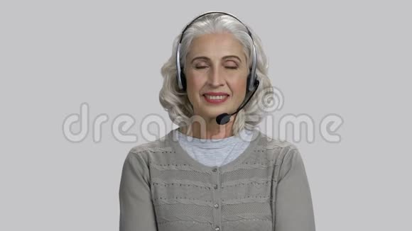 戴着耳机微笑的漂亮老太太视频的预览图