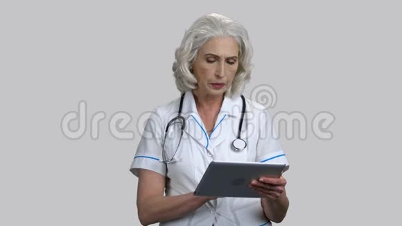 严重的老年女性医生使用平板电脑设备视频的预览图