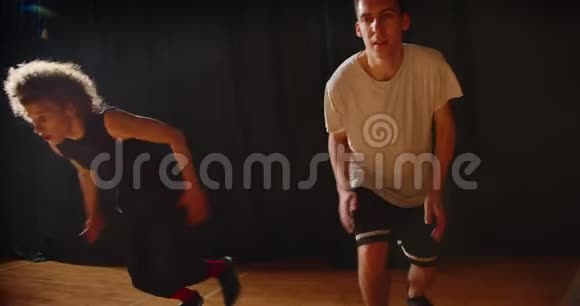 两名男青年篮球运动员穿梭比赛宴会厅晚上光线训练耐力视频的预览图