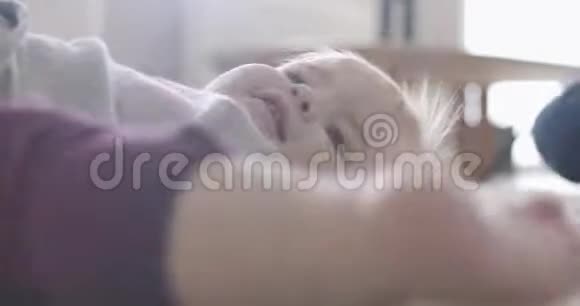 可爱开朗的女婴躺在柔软的地毯上微笑着阳光下漂亮的白人孩子的肖像电影院视频的预览图