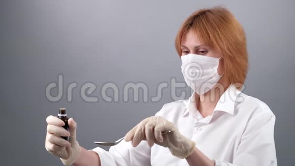 女医生的特写她的手从一个瓶子滴到一个勺子女性医生软焦医疗面具视频的预览图