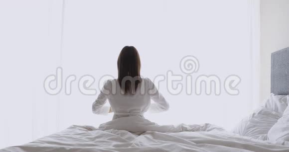 精力充沛的年轻黑发女人穿着睡衣醒来后伸展回来视频的预览图