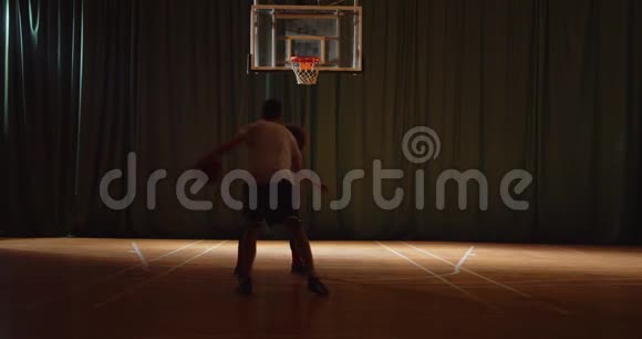 两名年轻的篮球运动员打篮球比赛对峙防守进攻夜场比赛黑暗剪影视频的预览图