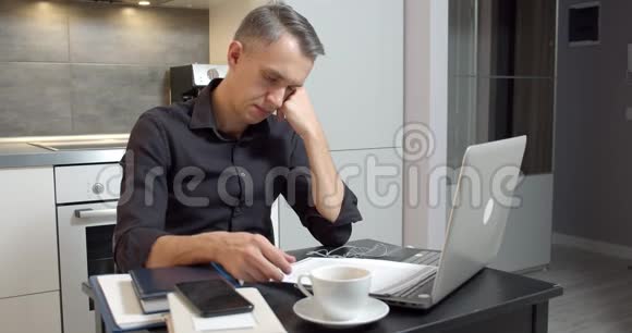 商人在家看文件在笔记本电脑上工作视频的预览图