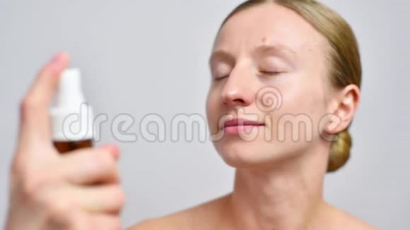 美丽的女人在脸上喷着微波视频的预览图