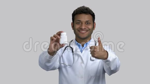 快乐的深色皮肤医生的肖像药瓶和拇指向上视频的预览图