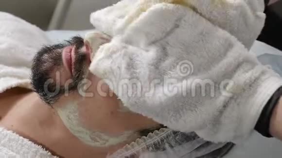 男性美容面部手术特写镜头擦出保湿面膜双手戴手套的美容师视频的预览图