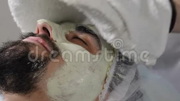 男性美容面部手术特写镜头擦出保湿面膜双手戴手套的美容师视频的预览图