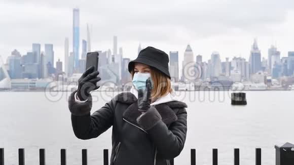 在纽约背景下使用智能手机进行视频聊天的妇女戴着病毒和流感防护面罩视频的预览图