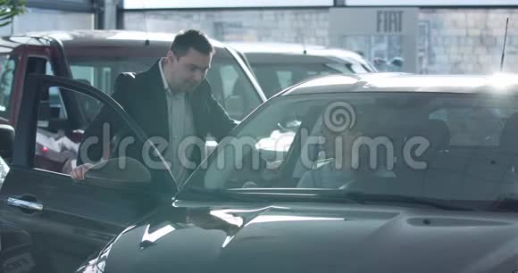 年轻的高加索女人坐在车里和毒贩说话经销商帮助客户选择经销商的车辆视频的预览图