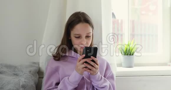 十几岁的女孩在家里使用手机应用程序持有智能手机视频的预览图