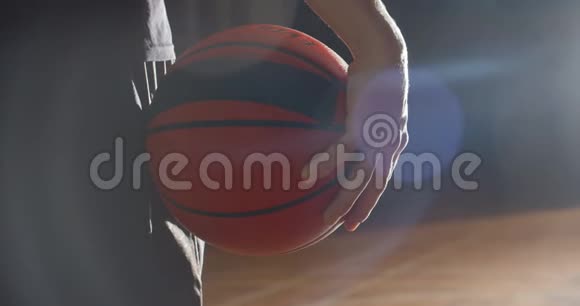 篮球运动员举着一个球的特写镜头明亮的光影剪影闪光视频的预览图