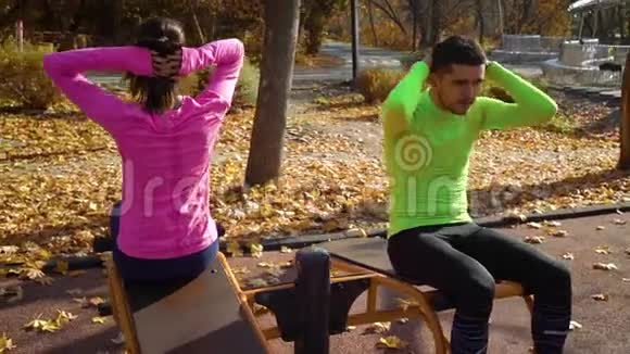 秋天在运动场上做腹部运动的年轻家庭视频的预览图