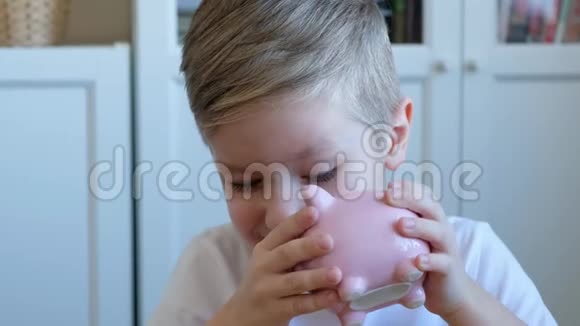 可爱的小男孩把一枚硬币放进储蓄罐里关上视频的预览图