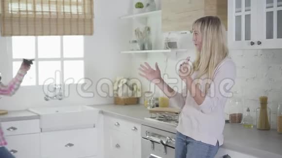 积极的高加索女人带着酒杯走进厨房快乐的女性朋友周末在家休息视频的预览图