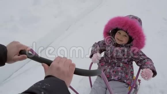 一个小女孩喜欢坐雪橇父母用雪橇载着孩子视频的预览图