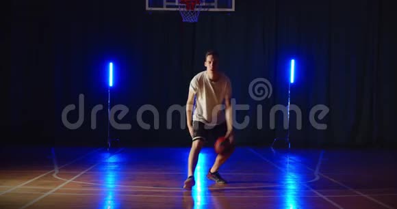年轻的白种人篮球运动员运球训练球技霓虹蓝光背景视频的预览图