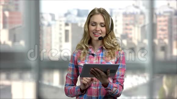 带耳机和平板电脑的年轻女人打字和说话视频的预览图
