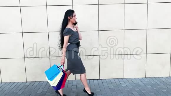 在黑色星期五假期一个女人拿着彩色的袋子在她的浅滩购物中心附近视频的预览图