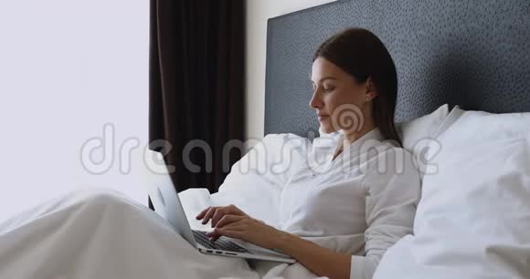 微笑的年轻女人在早上醒来后唱电脑视频的预览图
