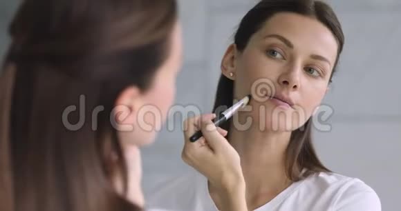 镜子反射迷人的年轻黑发女人做化妆视频的预览图
