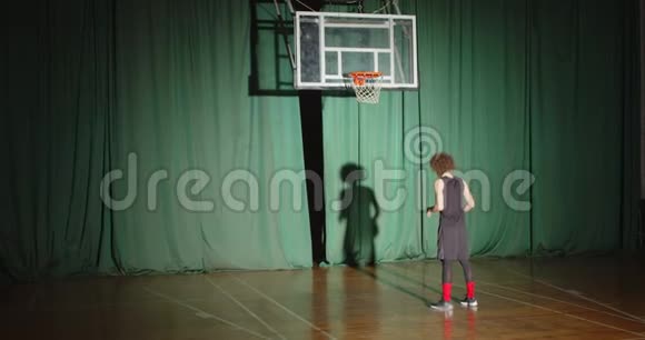 Curly篮球运动员看着篮筐拿着球准备自信单独阴影明亮光线比赛视频的预览图
