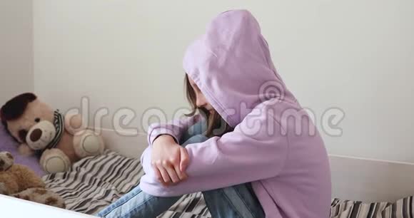 一个戴着兜帽的沮丧少女独自坐在床上视频的预览图