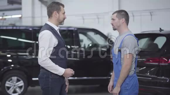 两个白种人站在汽车修理店边聊天成功的商人咨询汽车视频的预览图