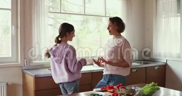 妈妈和女儿一起在厨房里跳着滑稽的舞蹈视频的预览图