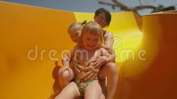 女人和她的孩子正在水上公园里沿着橙色的滑梯骑着视频的预览图