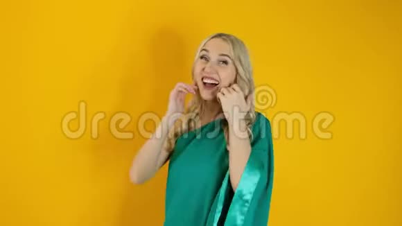 美丽快乐的金发女人在黄色背景下跳舞视频的预览图