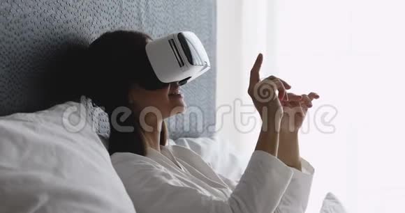 兴奋的微笑年轻的黑发女人使用虚拟现实护目镜视频的预览图