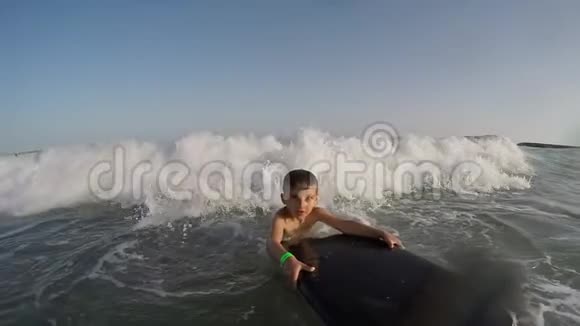 冲浪板上的男孩在海浪中嬉戏视频的预览图
