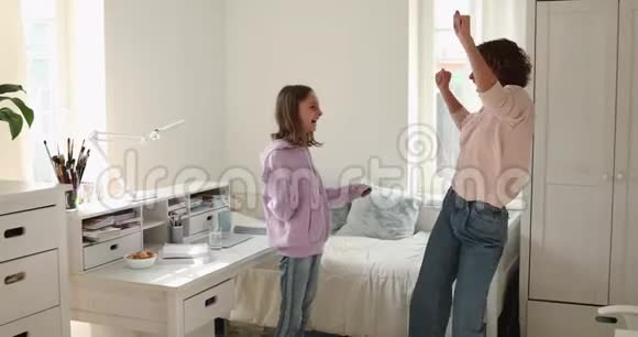快乐的妈妈和十几岁的女儿在家跳跳舞视频的预览图