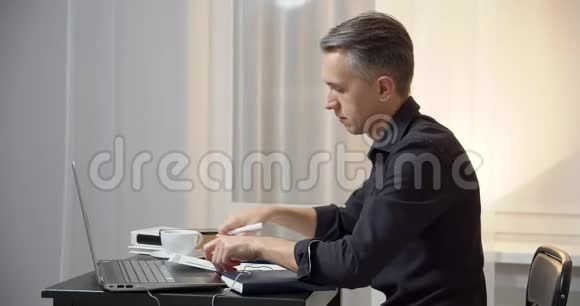商务人员在工作场所阅读文件并在笔记本电脑上键入文本或消息分析金融文件的男性企业家视频的预览图