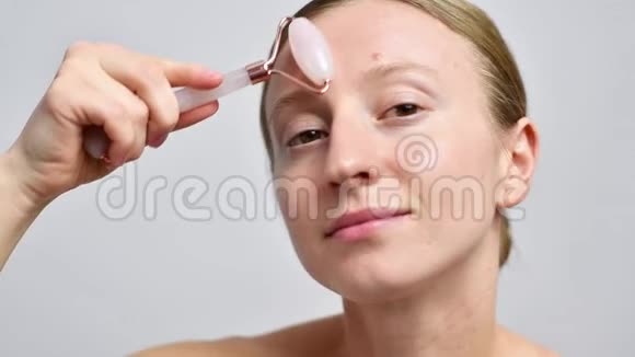 不化妆的女人用玉辊按摩脸部视频的预览图