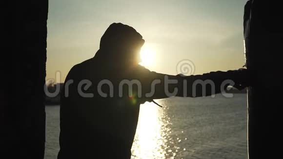 剪影拳击手在美丽的日落和河流上打拳击梨在露天锻炼拳击和武术视频的预览图