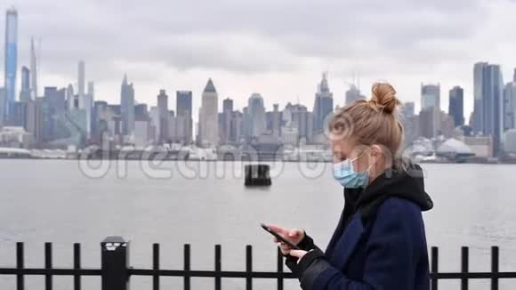 冠状病毒大流行在纽约背景下女人戴着智能手机防护面罩视频的预览图