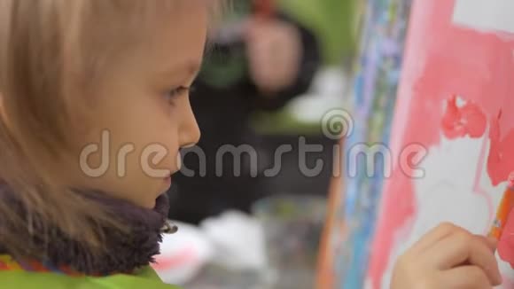 一个小女孩在一个艺术工作室里坐在画架上画画视频的预览图