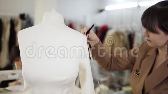 现代缝纫工作室集中深色头发的女时装设计师从一套白色西装的人体模型和袖子视频的预览图