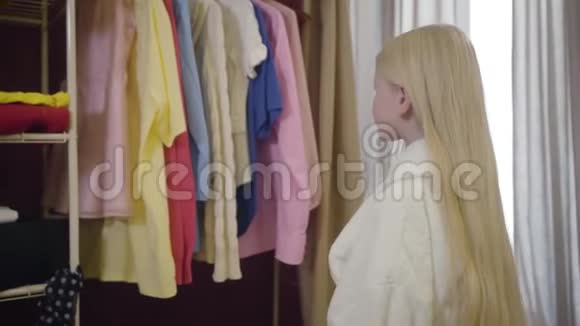 镜头放大漂亮的白种人女孩选择服装衣柜可爱的小女人站在她的房间里视频的预览图