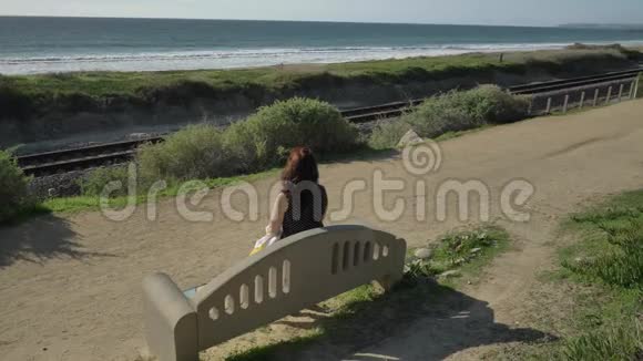 女人快乐美丽阳光明媚的夏日坐在长椅上在海洋海岸做头发旅行假期退休视频的预览图