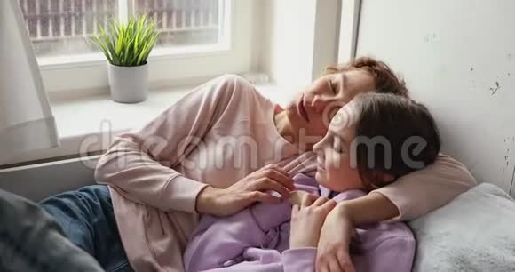 快乐的妈妈拥抱着十几岁的女儿说着轻松的躺在床上视频的预览图