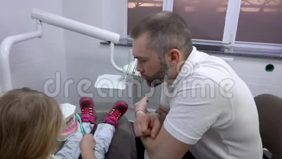 牙医向一个可爱的小女孩解释如何清洁她的牙齿视频的预览图
