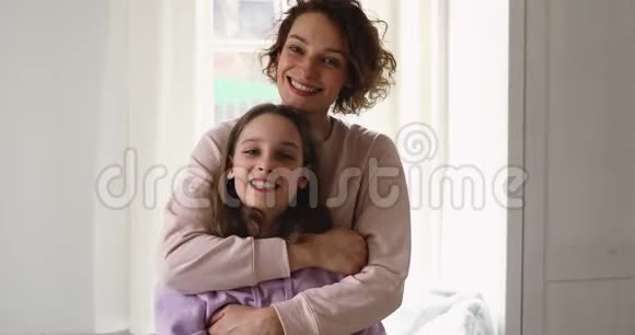 快乐深情的年轻妈妈抱着十几岁的女儿看镜头视频的预览图