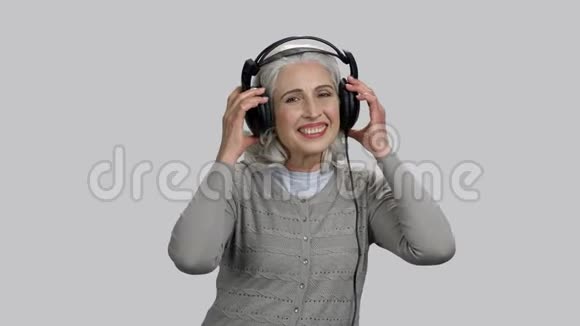 老太太用大耳机听和欣赏慢音乐视频的预览图
