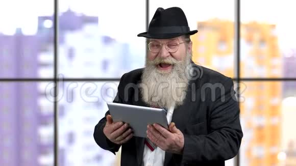 穿西装的老商人笑着看着平板电脑上有趣的模因视频的预览图