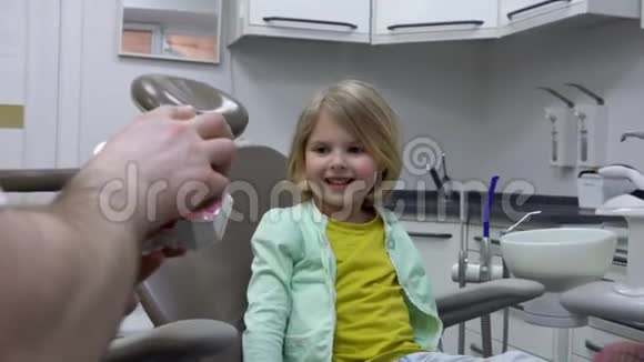 牙医向一个小女孩展示一个下巴模型来解释如何刷牙视频的预览图