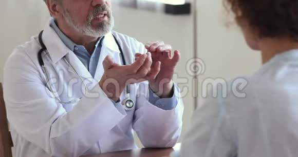 老年男性医生握手健康女性患者近距离观看视频的预览图
