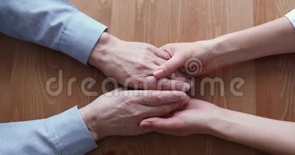 年轻的女儿或医生握着老男性的双手俯视视频的预览图